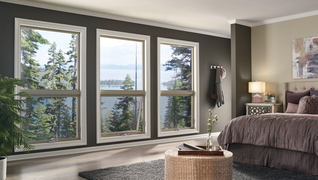 Master Bedroom with three large vinyl windows overlooking a lake fronted by evergreen trees