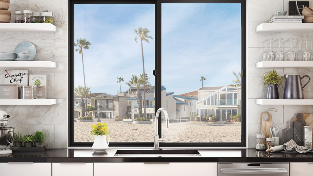 Kitchen sink with view of a sandy beach with tall palm trees seen through two sliding vinyl windows