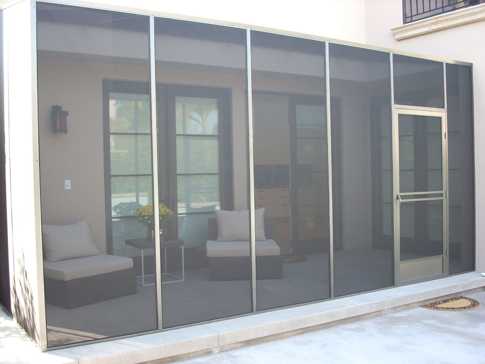 See into a porch/patio area which is totally enclosed by window screens that extend across the whole back of the house 