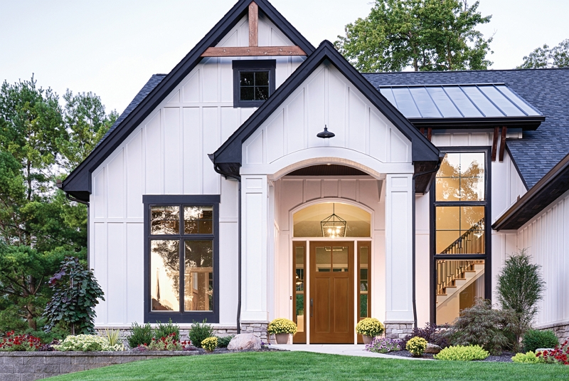 Exterior view of wood clad home with multiple cathedral ceilings and fiberglass entry door.