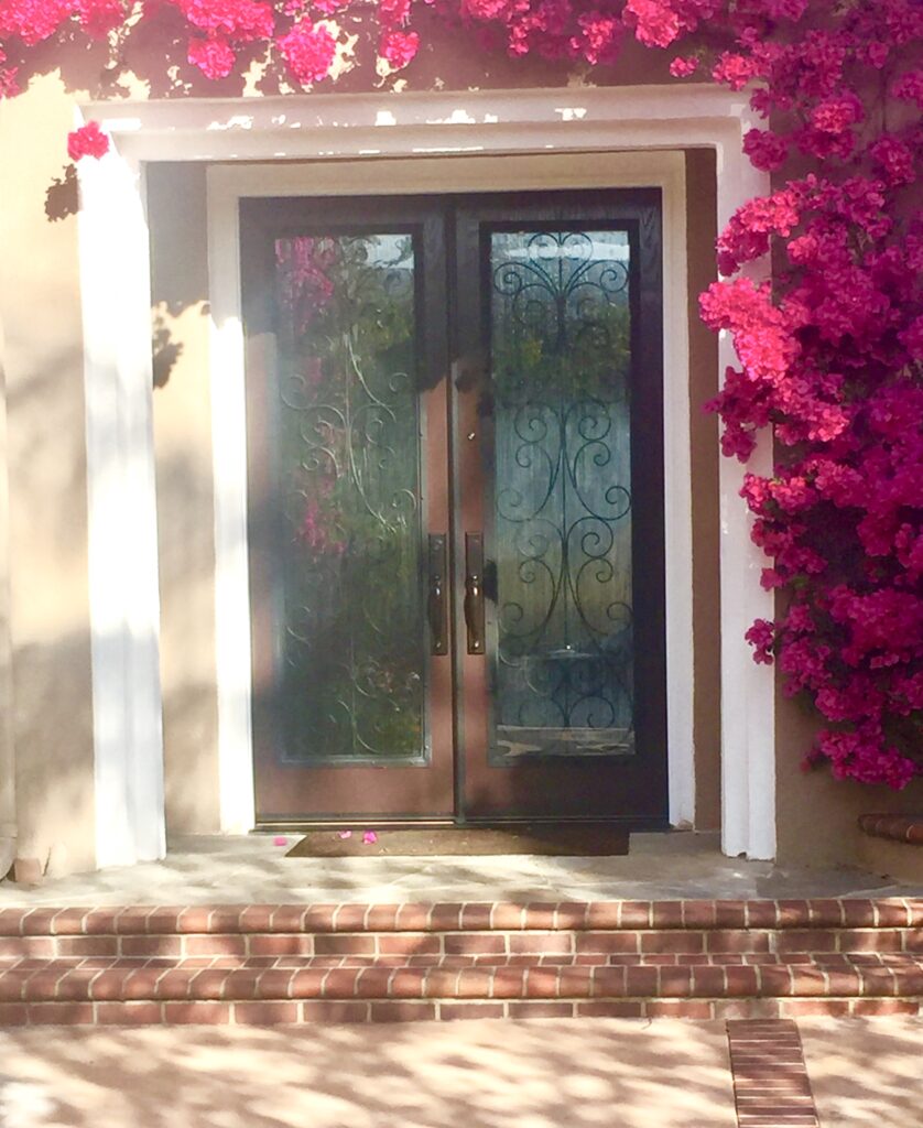 Elegant double entry doors with ornate wrought iron insets.