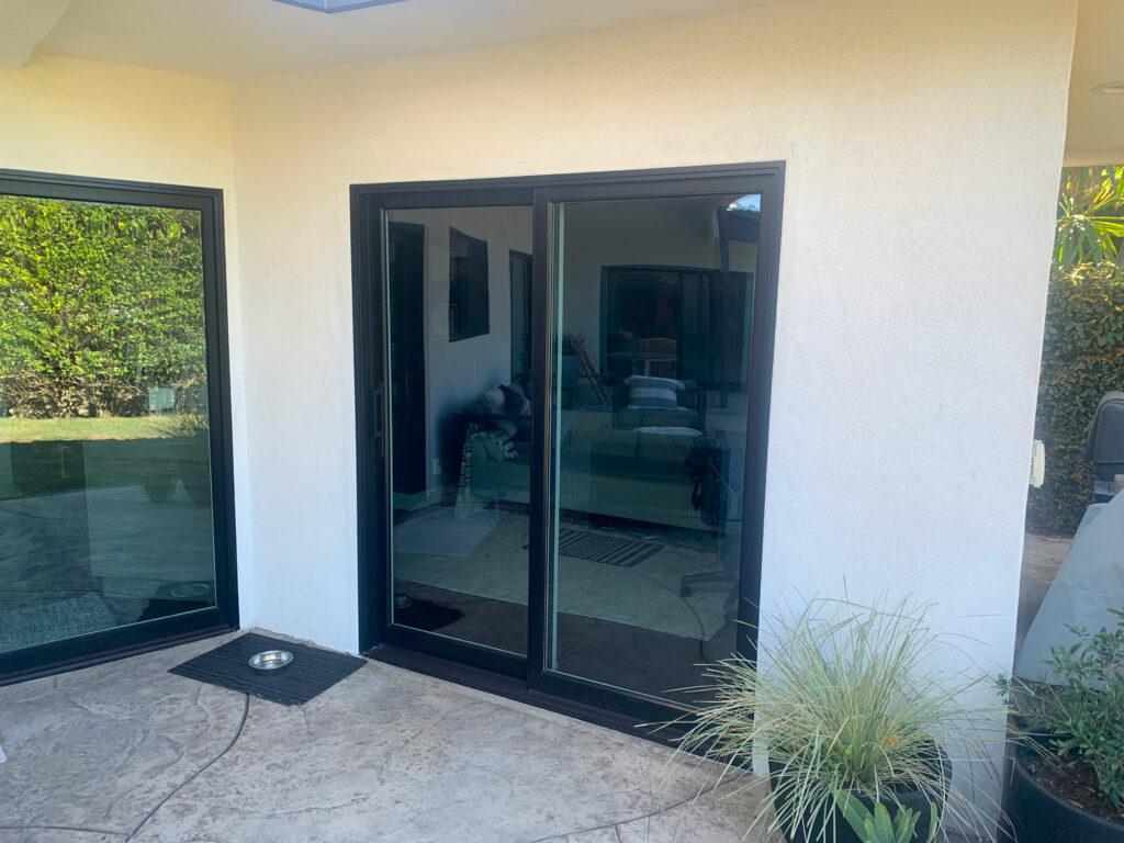 Black frame sliding glass door opening to a backyard.