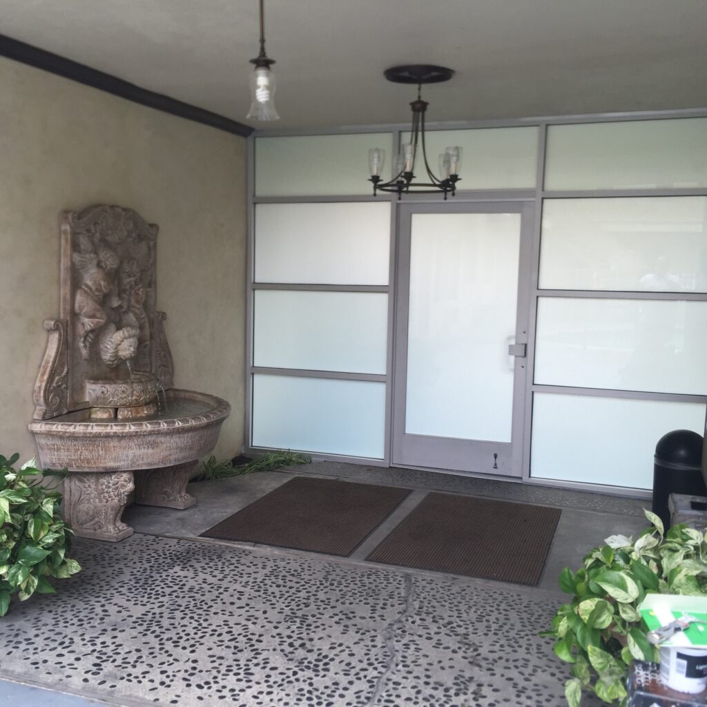 Elegant entrance with frosted glass storefront doors and a water fountain.