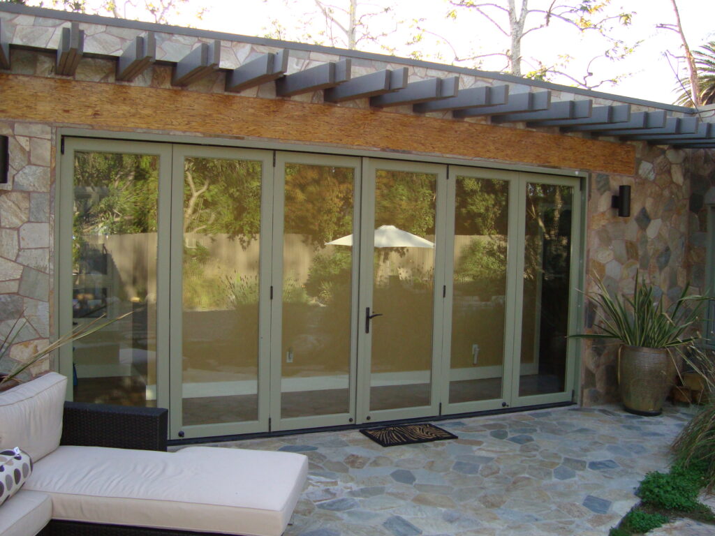 Modern sliding glass doors with a stone facade and outdoor seating area.