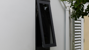 Modern black steel window partially open on a white exterior wall, showcasing minimalist design