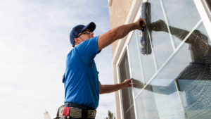 Professional window cleaner using a squeegee on a large glass window, achieving streak-free results