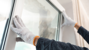 Professional performing window installation with protective gloves.